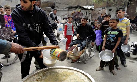  Volunteers distribute free meals to residents at the Palestinian refugee camp of Yarmouk. Photograph: Reuters 
