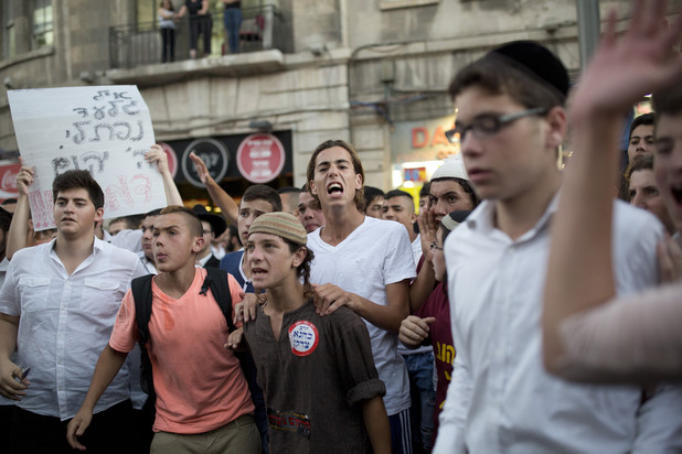 At a right-wing protest in Jerusalem a sign reads “May God avenge their blood” and a youth wears a sticker stating “Kahane was right,” referring to the Brooklyn-born violent settler movement leader, 1 July. (Tali Mayer / ActiveStills)